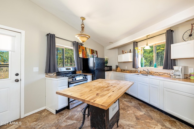 kitchen with pendant lighting, white cabinetry, stainless steel range with gas stovetop, and black fridge