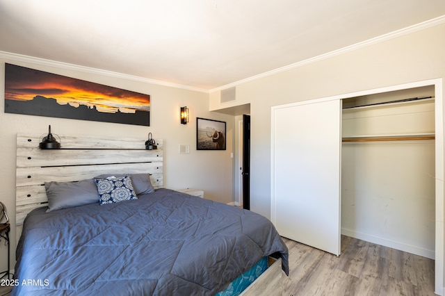 bedroom with hardwood / wood-style floors, crown molding, and a closet