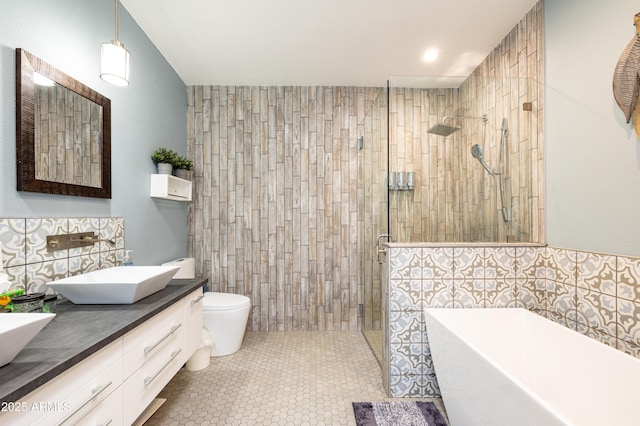 full bathroom with tile patterned floors, toilet, tile walls, vanity, and independent shower and bath