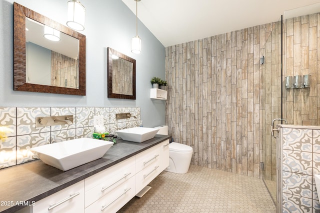 bathroom featuring vanity, toilet, a shower with door, and tile walls