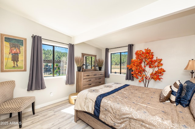 bedroom with light hardwood / wood-style flooring and beamed ceiling