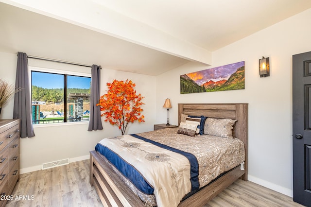 bedroom with beamed ceiling and light hardwood / wood-style flooring