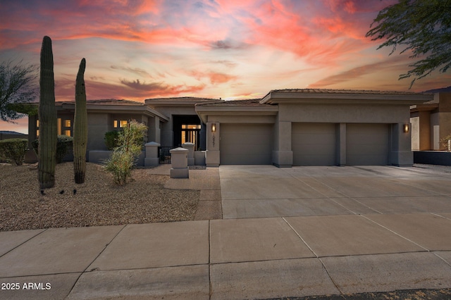 prairie-style home with an attached garage, driveway, and stucco siding