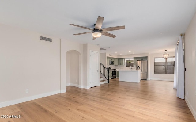 20929 N 37th Way, Phoenix, AZ 85050 - unfurnished living room featuring arched walkways, stairs, ceiling fan, light wood-style floors, and baseboards