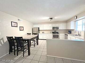 kitchen featuring white cabinets, sink, light tile patterned flooring, and stainless steel appliances