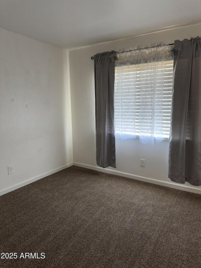 spare room featuring carpet floors and baseboards