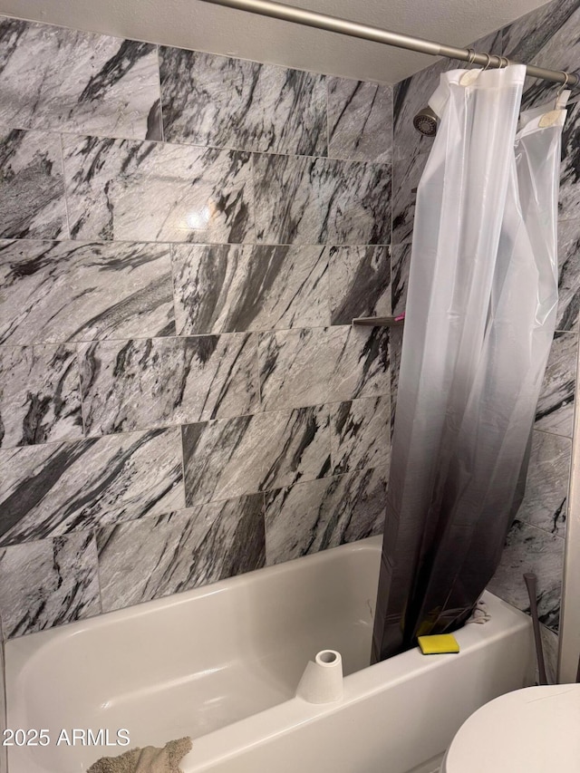 bathroom featuring toilet, a textured ceiling, and shower / tub combo with curtain