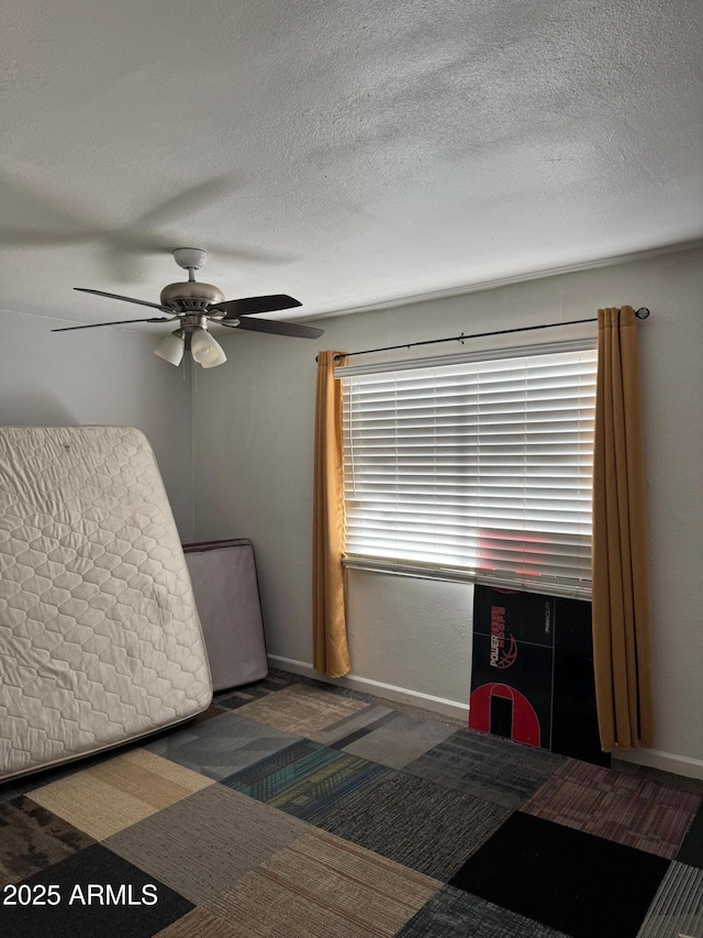 bedroom with ceiling fan, baseboards, and a textured ceiling