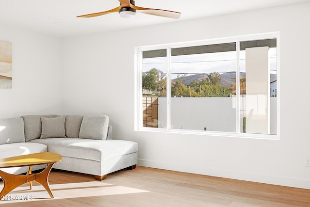 living room featuring ceiling fan, a mountain view, and light hardwood / wood-style floors