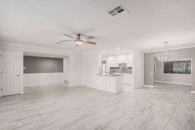 unfurnished living room with ceiling fan with notable chandelier and ornamental molding