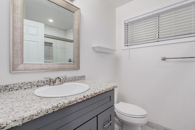 bathroom featuring vanity, a shower with shower door, and toilet