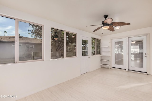 unfurnished sunroom featuring ceiling fan