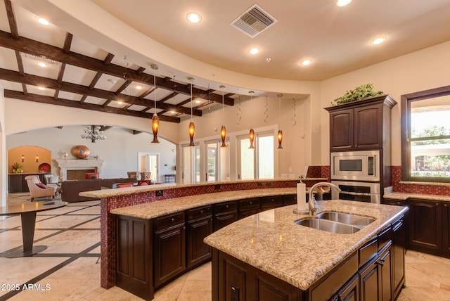 1367 S Country Club Dr S Unit 1125, Mesa, AZ 85210 - kitchen with appliances with stainless steel finishes, a kitchen island with sink, a fireplace, beamed ceiling, and recessed lighting
