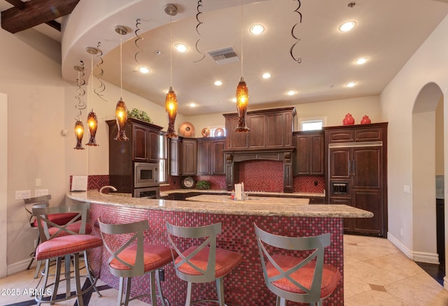 1367 S Country Club Dr S Unit 1125, Mesa, AZ 85210 - kitchen featuring built in appliances, arched walkways, a kitchen breakfast bar, a peninsula, and light stone countertops