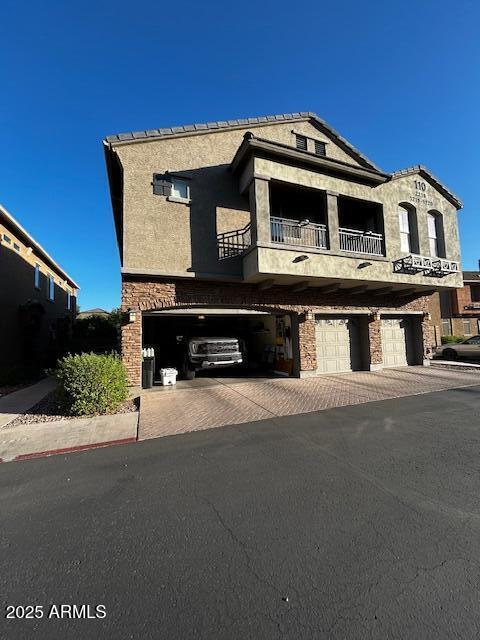 1350 S Greenfield Rd Unit 1219, Mesa, AZ 85206 - view of front of home featuring a garage, a balcony, decorative driveway, and stone siding