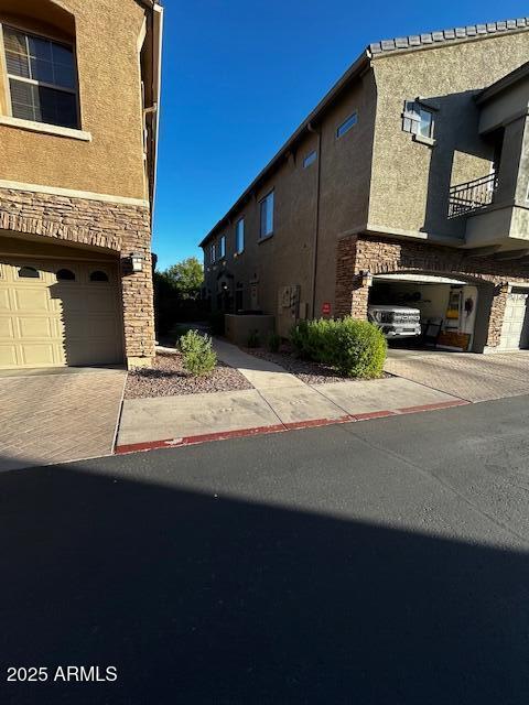 1350 S Greenfield Rd Unit 1219, Mesa, AZ 85206 - view of side of property featuring stone siding, stucco siding, and a garage
