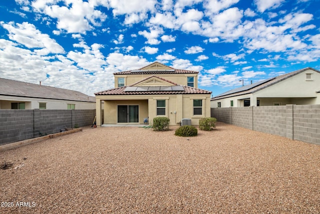 back of property with central AC, solar panels, and a patio