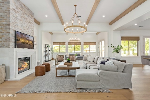 living room with a healthy amount of sunlight, beam ceiling, a fireplace, and a notable chandelier