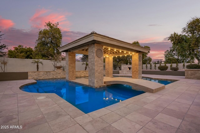 pool at dusk featuring a gazebo and a patio