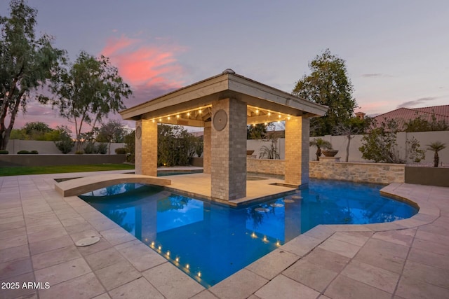 pool at dusk with a gazebo and a patio