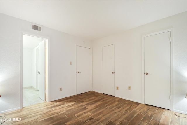 unfurnished bedroom featuring wood-type flooring and ensuite bathroom