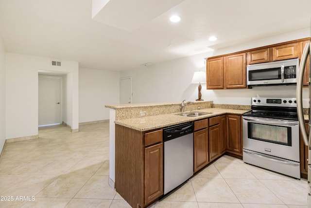 kitchen featuring sink, light tile patterned floors, kitchen peninsula, stainless steel appliances, and light stone countertops