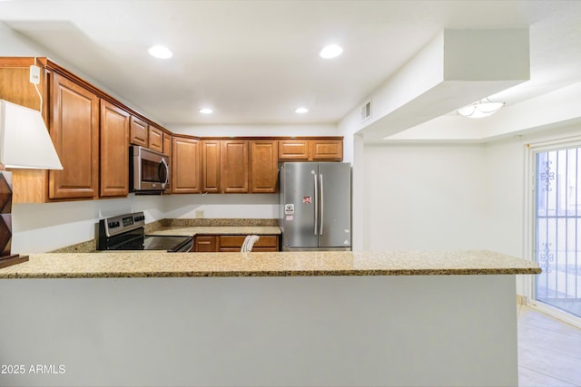 kitchen with appliances with stainless steel finishes, light tile patterned floors, light stone counters, and kitchen peninsula