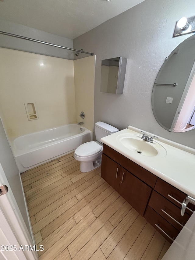 bathroom with toilet, vanity, tub / shower combination, and wood finished floors