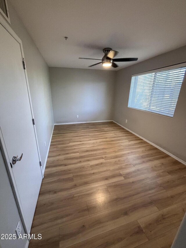 interior space with baseboards, visible vents, wood finished floors, and ceiling fan