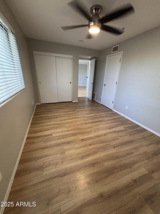 unfurnished bedroom featuring wood finished floors, baseboards, and visible vents