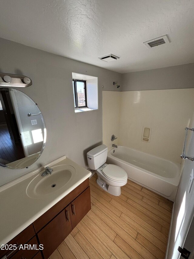 bathroom with toilet, visible vents, wood finished floors, and washtub / shower combination