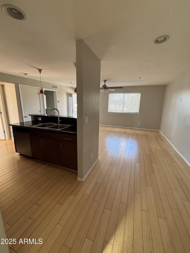kitchen featuring dark countertops, a ceiling fan, a sink, light wood-type flooring, and open floor plan