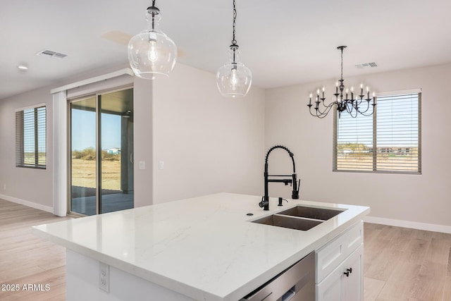 kitchen with sink, dishwasher, an island with sink, white cabinets, and decorative light fixtures