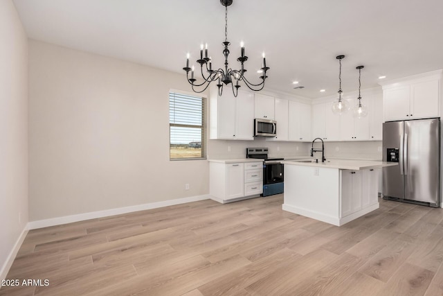 kitchen featuring decorative light fixtures, stainless steel appliances, an island with sink, and white cabinets