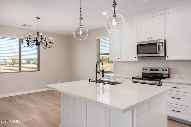 kitchen with a kitchen island with sink, sink, decorative light fixtures, and stainless steel appliances