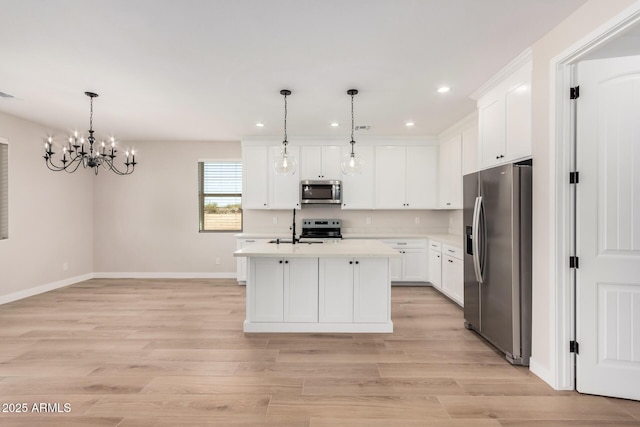 kitchen featuring pendant lighting, white cabinetry, stainless steel appliances, and an island with sink