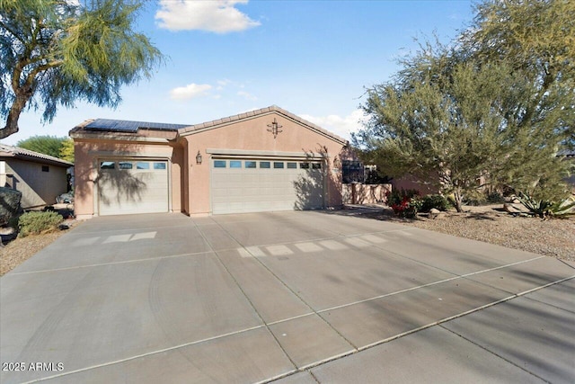 view of front of house with a garage, solar panels, a tile roof, driveway, and stucco siding