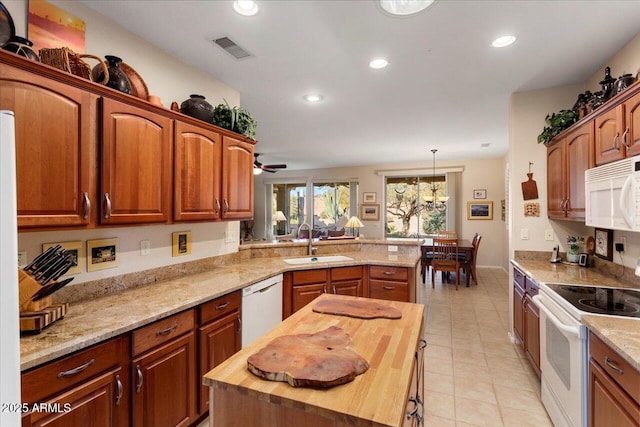 kitchen featuring white appliances, a kitchen island, a peninsula, wooden counters, and a sink