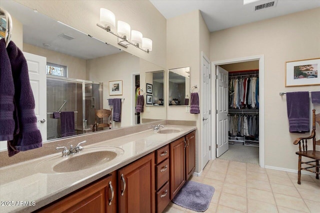 bathroom featuring a spacious closet, double vanity, a stall shower, and visible vents