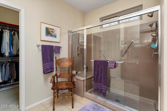 full bath with a stall shower, tile patterned flooring, a walk in closet, and baseboards