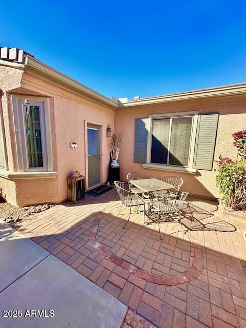 rear view of house featuring a patio, outdoor dining area, and stucco siding