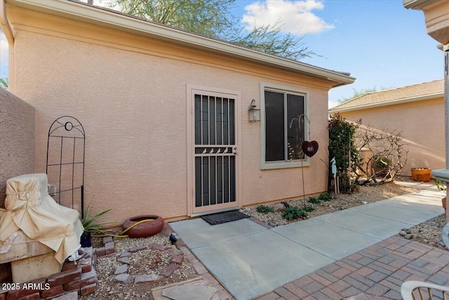 view of exterior entry featuring a patio area and stucco siding