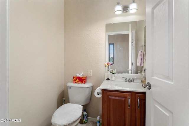 half bath with a textured wall, vanity, and toilet