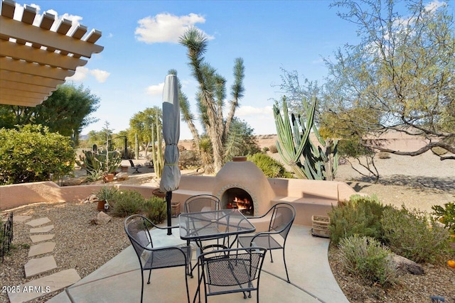 view of patio / terrace with a lit fireplace and outdoor dining space