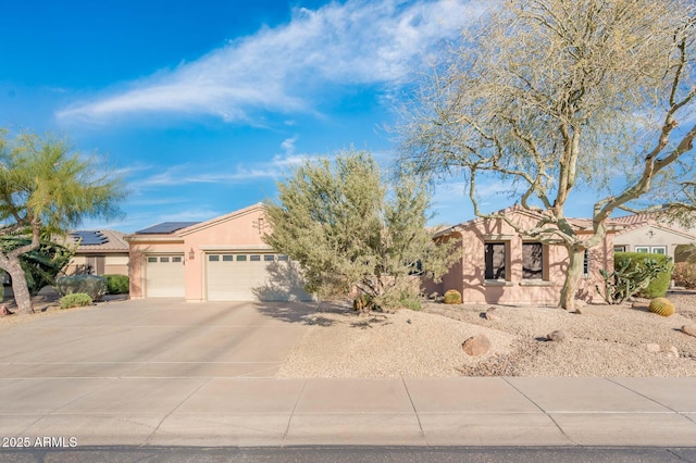 view of front facade featuring stucco siding, solar panels, an attached garage, driveway, and a tiled roof