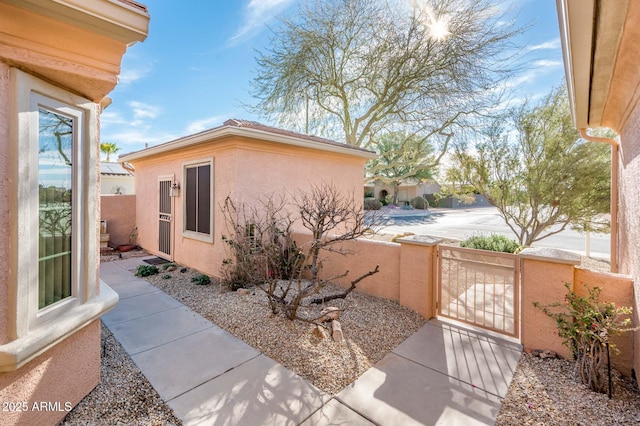 view of property exterior featuring a gate, fence, and stucco siding