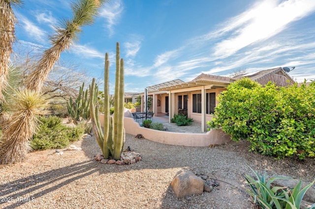 exterior space with a patio, stucco siding, a tile roof, and a pergola