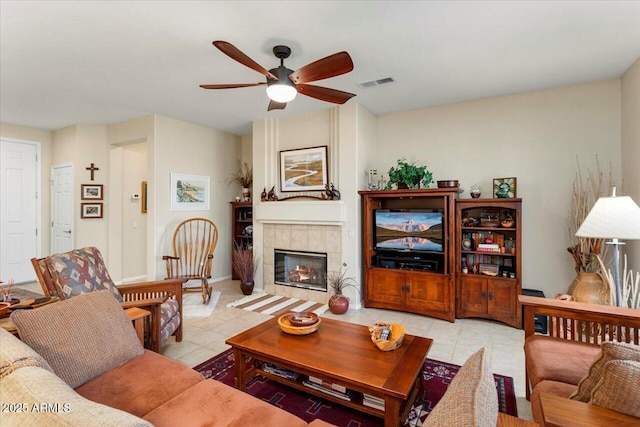 living room featuring ceiling fan, light tile patterned floors, and a tile fireplace