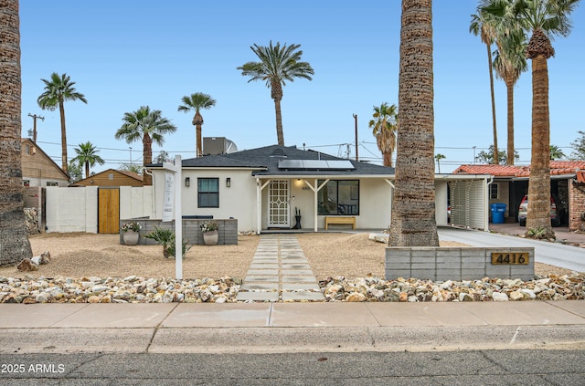 view of front of property featuring stucco siding, fence, concrete driveway, and a carport