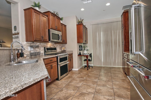 kitchen with sink, appliances with stainless steel finishes, backsplash, light stone countertops, and light tile patterned flooring